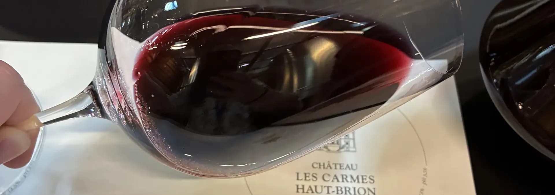 Rotweinglas über der Verkostungskarte von Château Les Carmes Haut-Brion — eigene Aufnahme