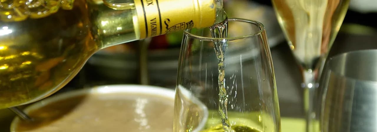 Goldgelber Sauternes wird ins Glas eingeschenkt